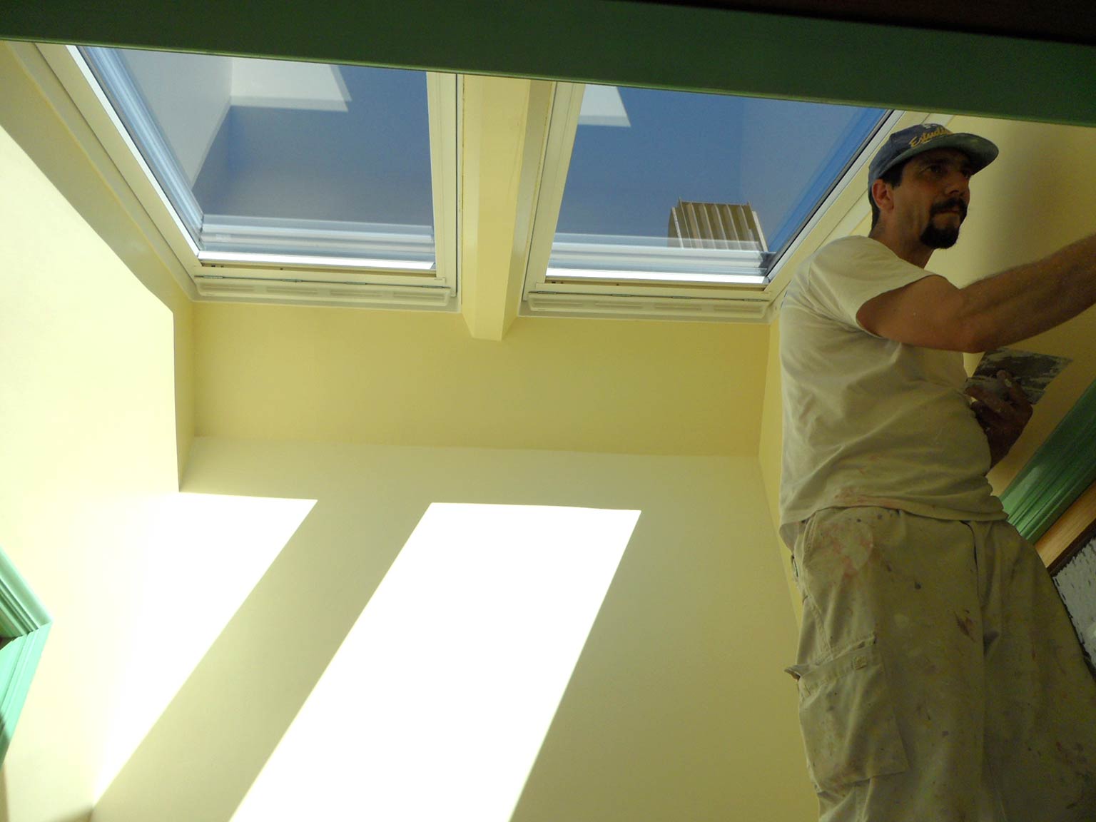 Detalle trabajador rematando el interior de dos ventanas Velux en Antonio Machado.